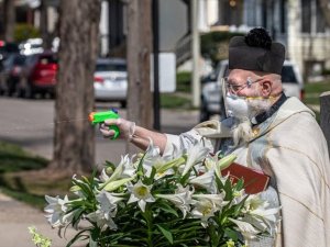 Rahip vatandaşları kutsal su tabancasıyla kutsuyor