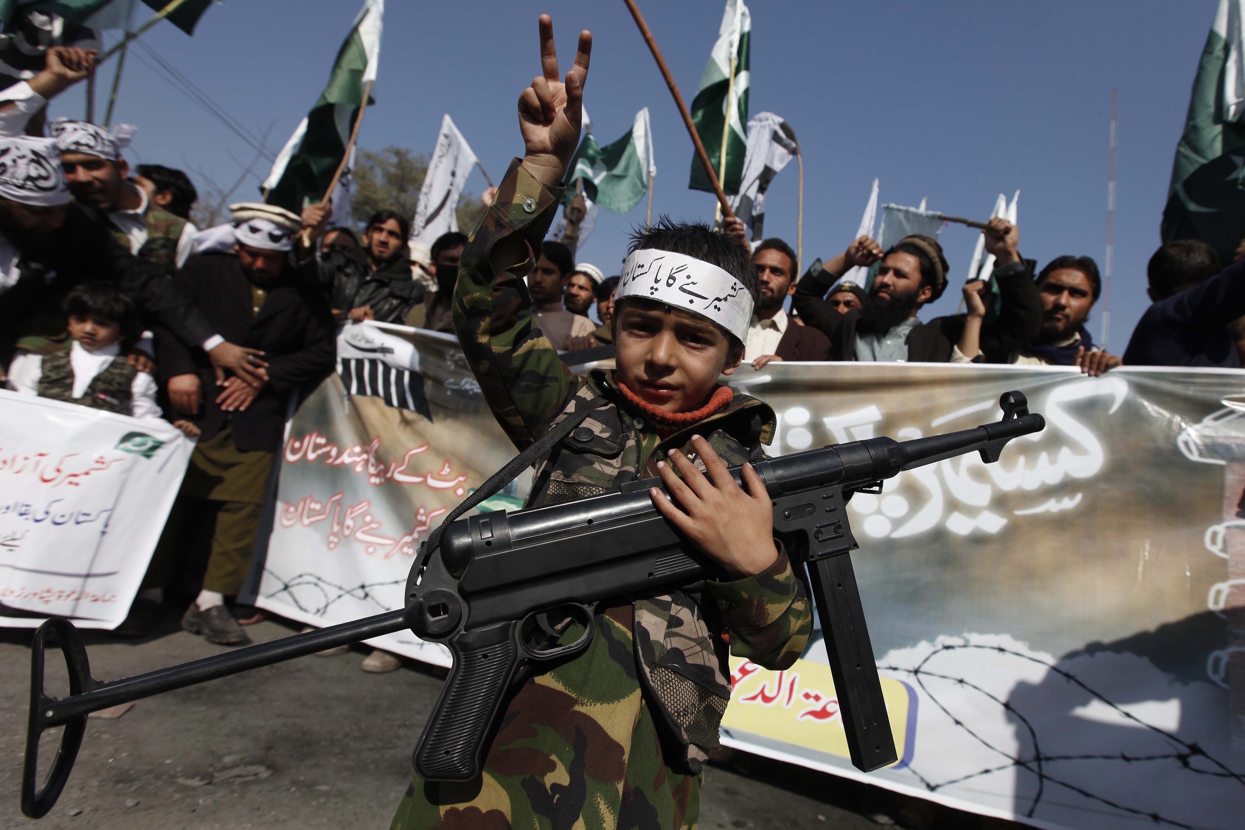epa05144283 A boy holds a weapon as supporters of the banned Pakistan-based charity Jamaat-ud-Dawa (JuD), attend a rally expressing support for Kashmiris lving in Indian Kashmir, in Peshawar, Pakistan, 05 February 2016. Demonstrators demanded an end to Indian rule in the region and a settlement of the dispute according to wishes of Kashmiris and UN resolutions. EPA/ARSHAD ARBAB