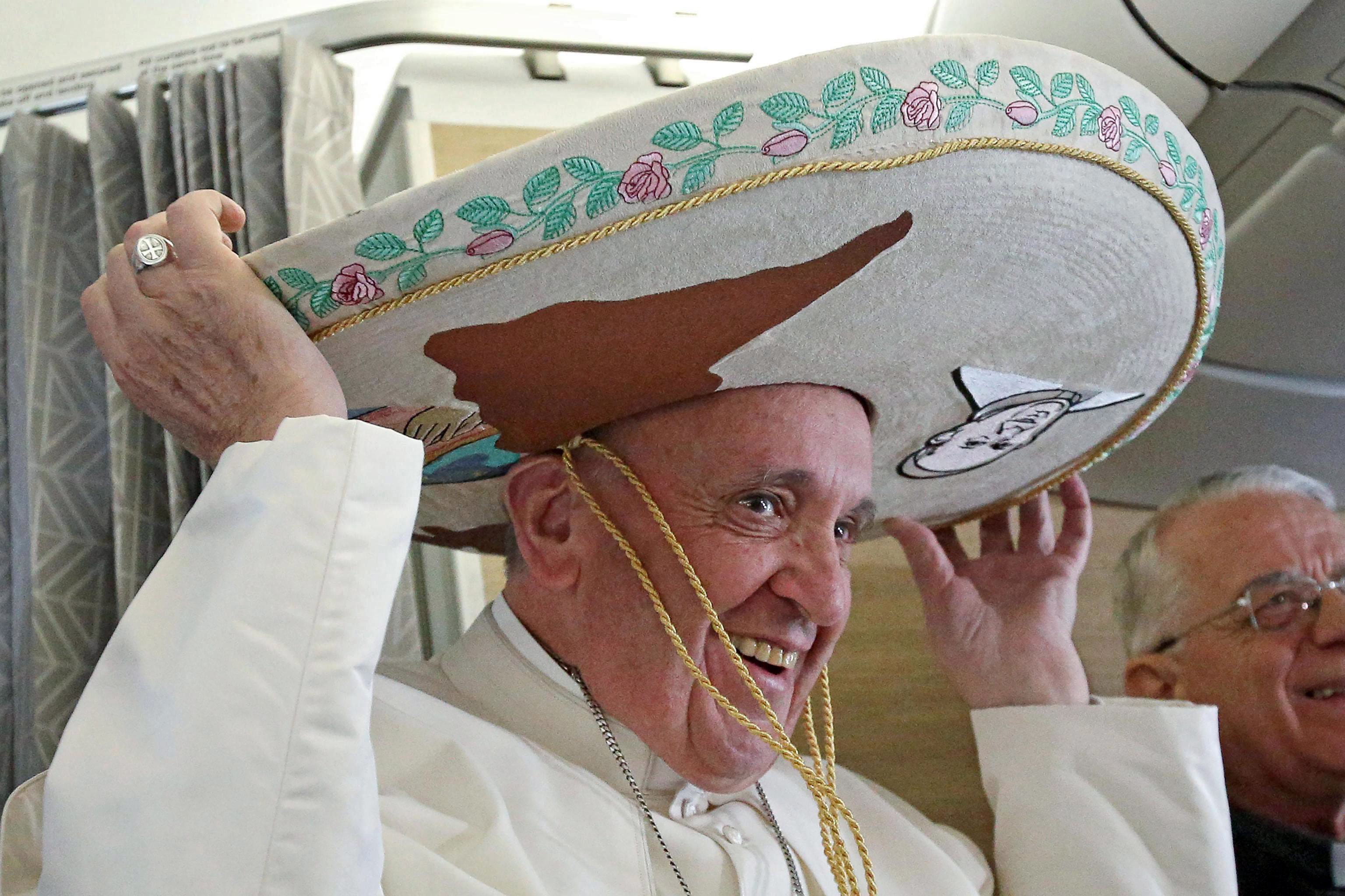 epa05155979 Pope Francis wears a sombrero hat he received as a gift by a Mexican journalist aboard of the airplane to Havana, Cuba, 12 February 2016. Pope Francis visits Cuba and Mexico from 12 to 18 February 2016. EPA/ALESSANDRO DI MEO / POOL